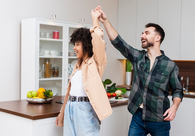 Gelukkige man en vrouw die in keuken dansen