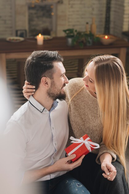 Gelukkige man met geschenkdoos in de buurt van vrolijke blonde vrouw