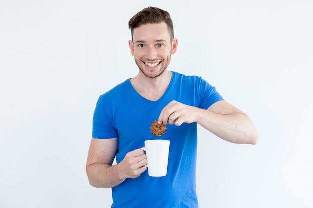 Gelukkige man onderdompelen koekje in warme drank