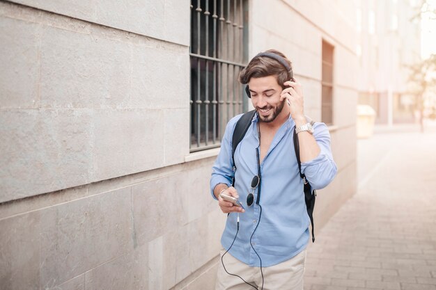 Gelukkige mens die op bestrating loopt die aan muziek luistert