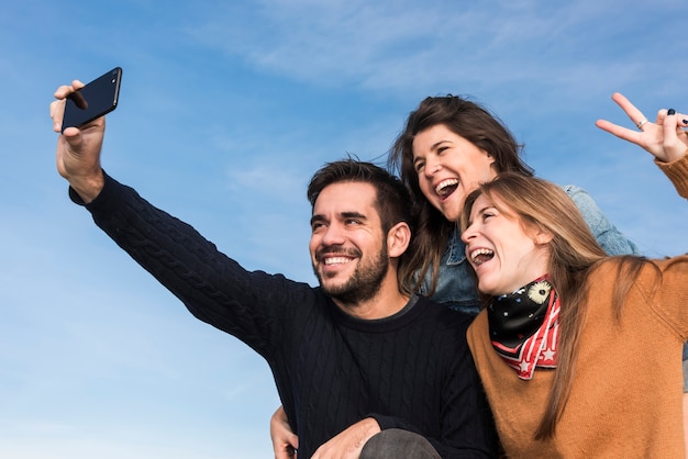 Gelukkige mensen die selfie op blauwe hemelachtergrond nemen