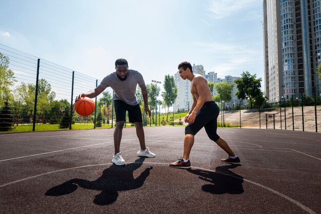 Gelukkige mensen die stedelijk basketbal afstandsschot spelen