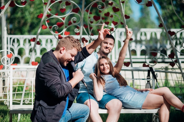 Gratis foto gelukkige mensen ontspannen op bank zingen lied en gebaren overwinning