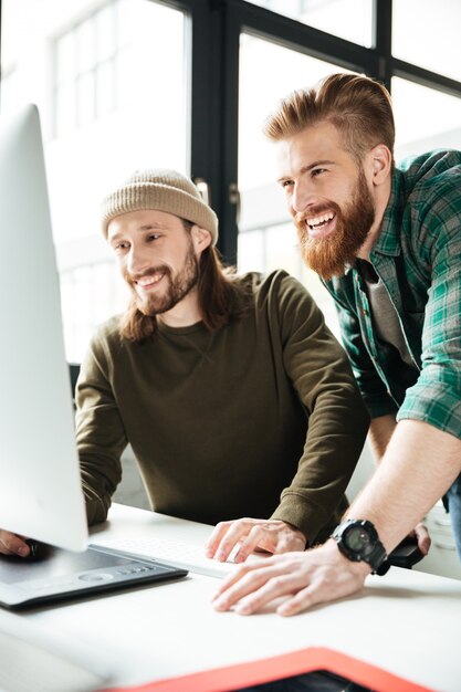 Gelukkige mensencollega's in bureau die computer met behulp van. Opzij kijken.