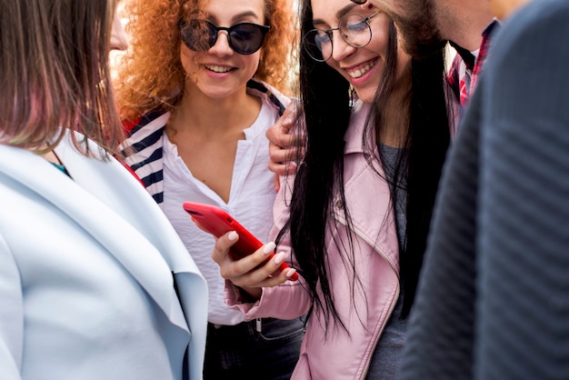 Gelukkige modieuze groep vrienden die het mobiele telefoonscherm bekijken