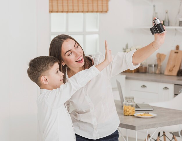 Gratis foto gelukkige moeder die een foto met zoon neemt