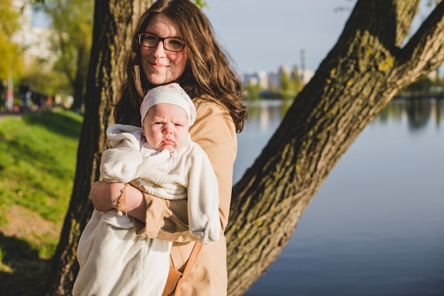 Gelukkige moeder die haar baby met meer achtergrond houdt