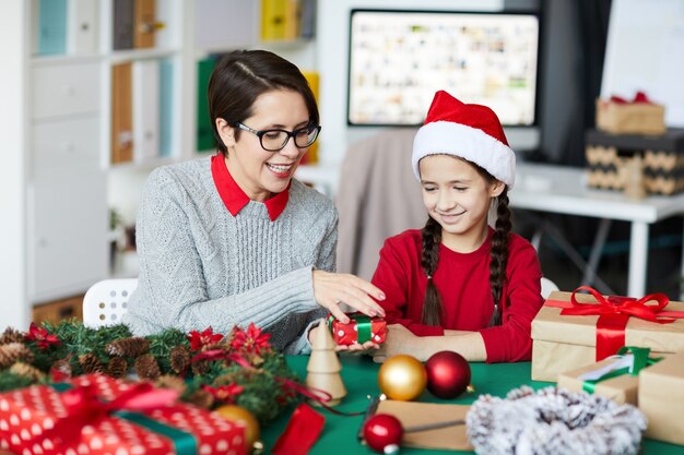 Gelukkige moeder en dochter die Kerstcadeaus verpakken