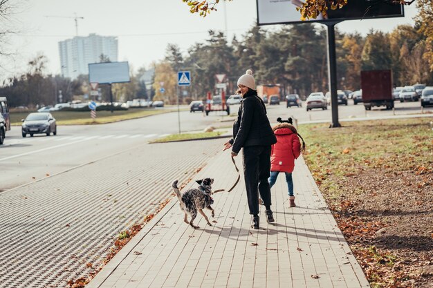 Gelukkige moeder en haar dochter lopen met hond op straat.