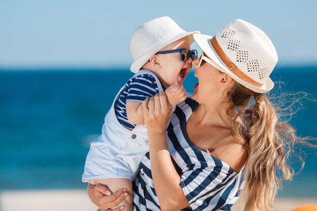 gelukkige moeder met kleine jongen die plezier heeft op het strand bij de zee