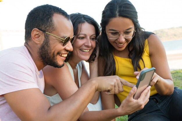 Gelukkige multi-etnische vrienden die smartphone gebruiken