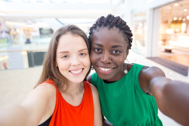 Gelukkige multietnische vrouwelijke vrienden die selfie nemen