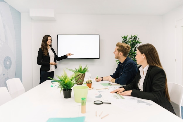 Gelukkige onderneemster die presentatie geven aan haar partners in commerciële vergadering