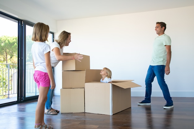 Gelukkige ouders en twee dochters die plezier hebben tijdens het uitpakken van dingen in hun nieuwe lege flat