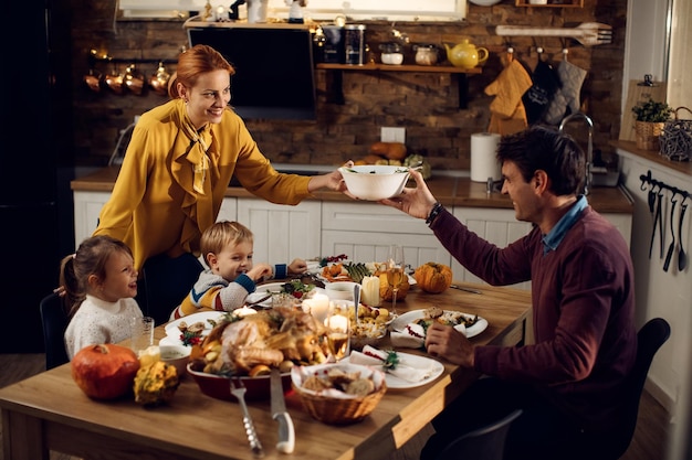 Gelukkige ouders met kinderen genieten van Thanksgiving-diner in de eetkamer