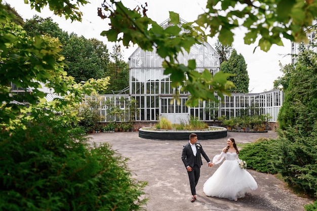 Gelukkige paar bruid en bruidegom wandelen in de gadren kijken elkaar met liefde mooi meisje in een gezwollen jurk met man in stijlvol pak tederheid moment verliefde paar