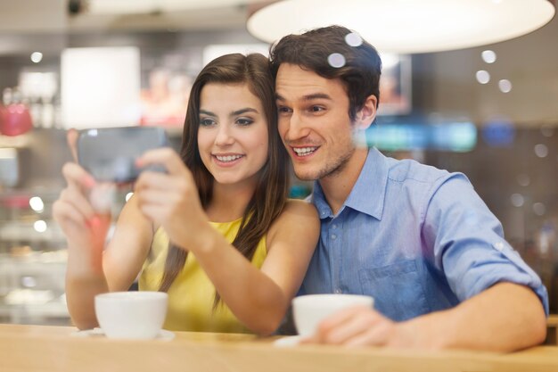 Gelukkige paar iets op mobiele telefoon in café controleren