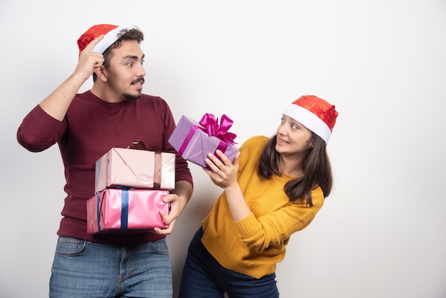 Gelukkige paar met kerstcadeaus over een witte muur.