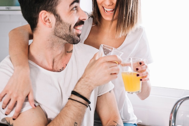 Gratis foto gelukkige paar rammelende glazen in keuken