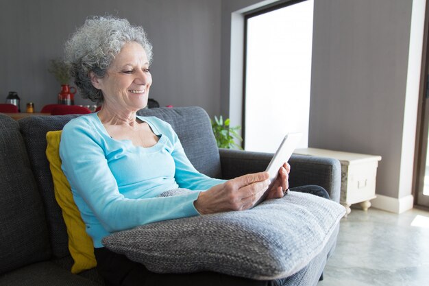 Gelukkige positieve bejaarde die tablet gebruikt