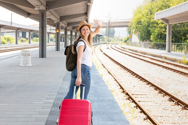 Gelukkige reiziger die bij het station glimlacht