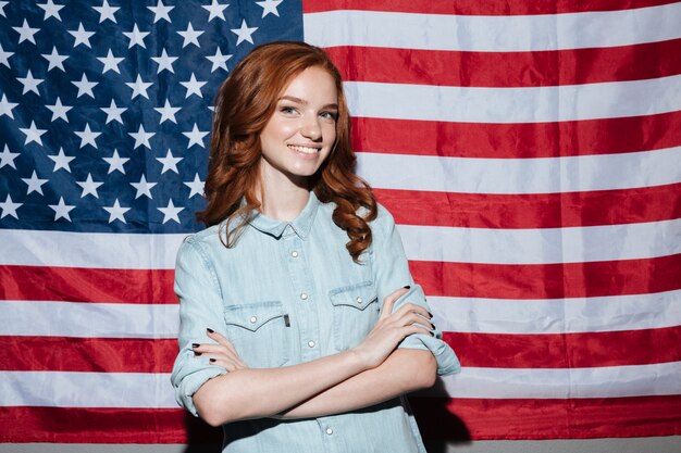 Gelukkige roodharige jonge dame die zich over de vlag van de VS bevindt
