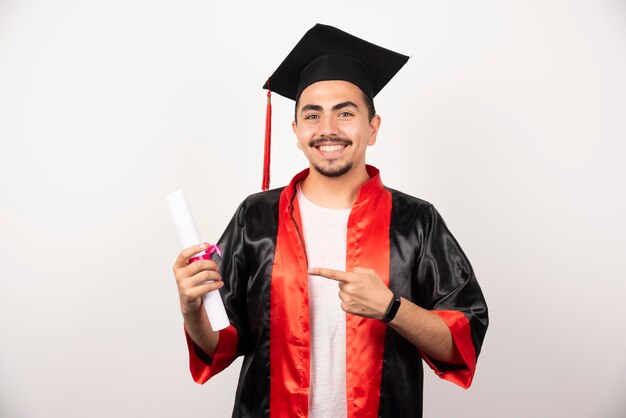 Gelukkige student die op diploma op wit richt.