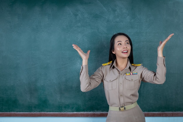 gelukkige Thaise leraar in officiële outfit die voor bord werkt