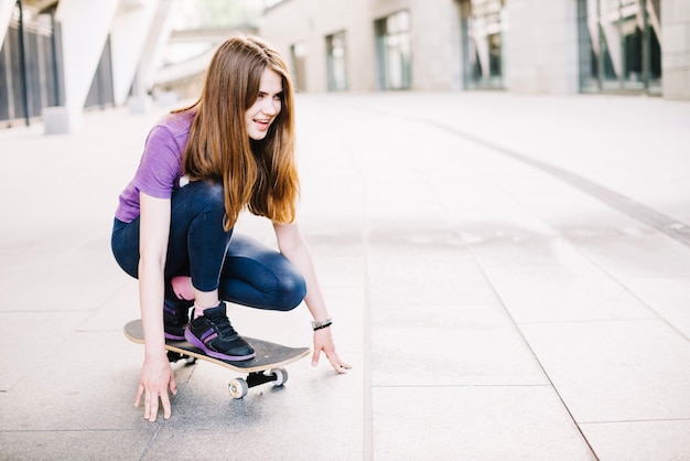 Gratis foto gelukkige tiener voorbereiding op skateboard rijden
