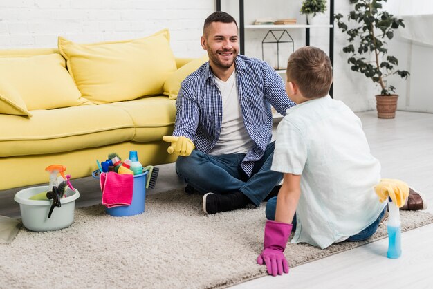 Gelukkige vader die aan zoon spreekt terwijl het schoonmaken
