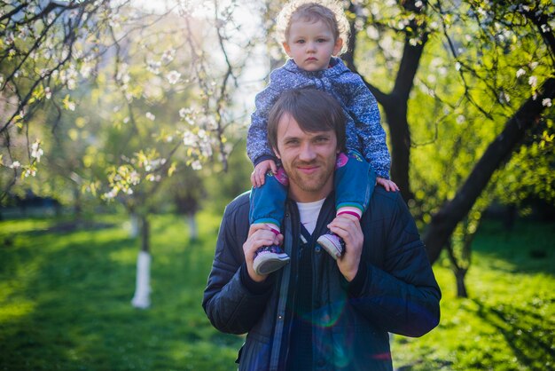 Gelukkige vader die met zijn zoon op zijn schouders staat