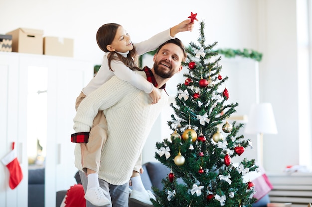 Gelukkige vader en dochter die de kerstboom versieren