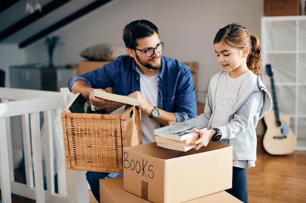 Gelukkige vader en dochter die hun spullen uitpakken terwijl ze naar een nieuw appartement verhuizen