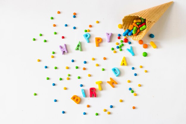 Gelukkige verjaardagstekst met snoepjes die van wafelijsje morsen