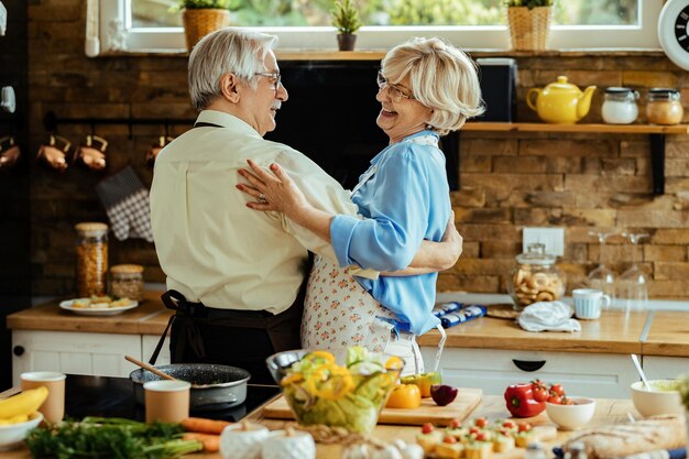 Gelukkige volwassen man en vrouw die plezier hebben tijdens het dansen in de keuken