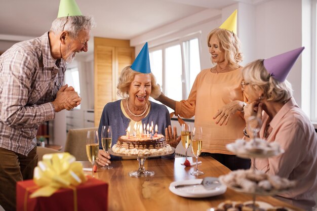 Gelukkige volwassen mensen die de verjaardag van vrienden vieren en thuis plezier hebben