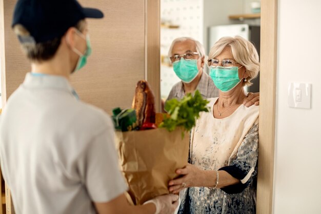 Gelukkige volwassen vrouw en haar man ontvangen thuis boodschappen tijdens de coronavirusepidemie