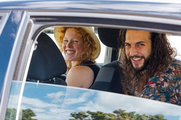 Gelukkige vrienden die in auto tijdens einde op de zomerdag zitten