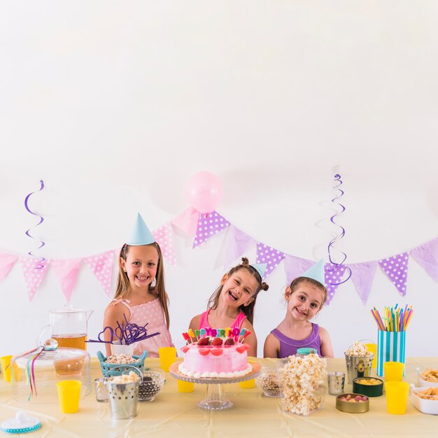 Gelukkige vrienden die verjaardag van partij met smakelijke snack en cake op lijst genieten