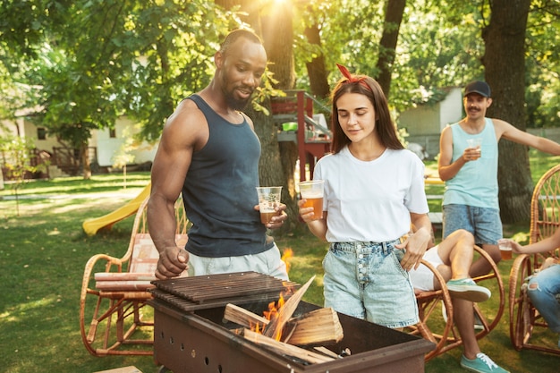 Gelukkige vrienden hebben bier en barbecue feest op zonnige dag