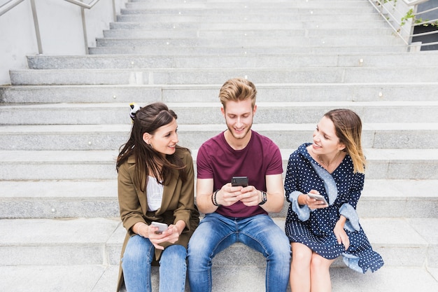 Gelukkige vriendenzitting op trap met smartphone