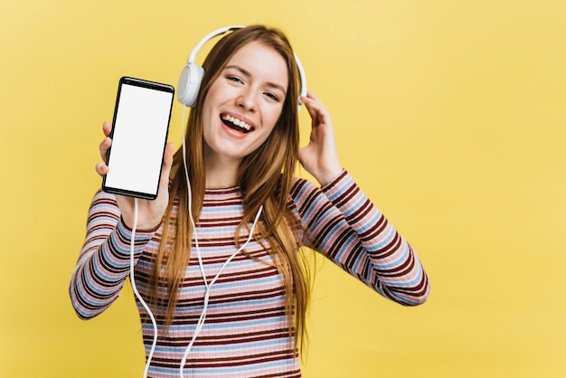 Gelukkige vrouw die aan muziek op telefoonmodel luistert