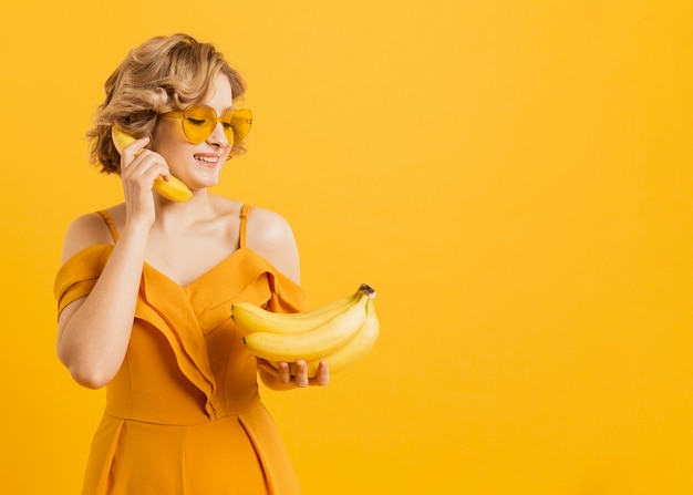 Gratis foto gelukkige vrouw die banaan gebruiken als telefoon