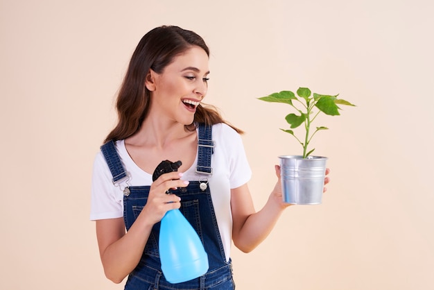 Gelukkige vrouw die de planten besproeit met insecticidespray