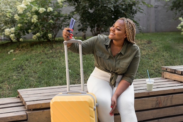 Gelukkige vrouw die een selfie naast haar bagage neemt