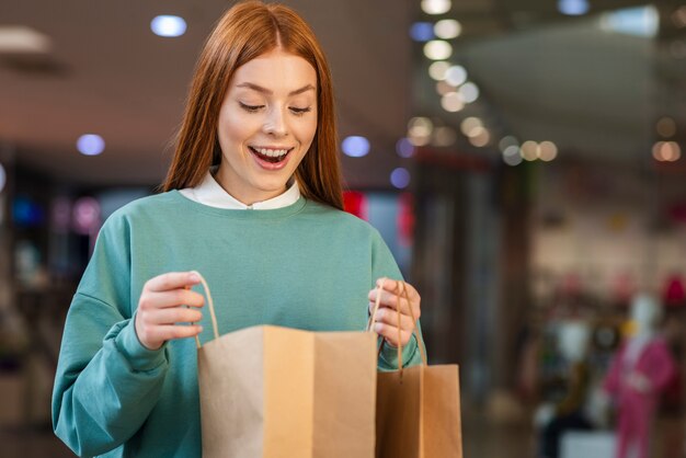 Gelukkige vrouw die in een het winkelen zak kijkt