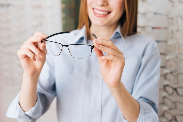 Gelukkige vrouw die nieuwe glazen zoekt bij optometrist