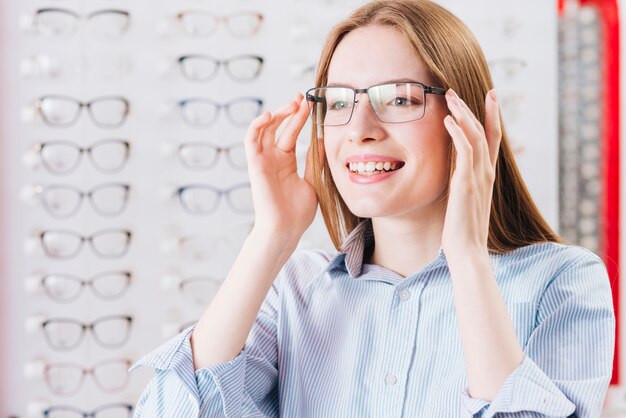 Gelukkige vrouw die nieuwe glazen zoekt bij optometrist