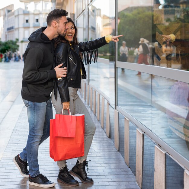 Gelukkige vrouw die op etalage aan de jonge mens toont