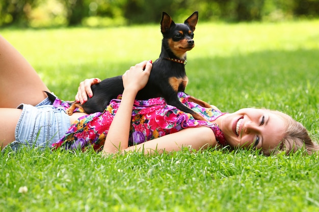 Gratis foto gelukkige vrouw die op het gras met haar hond ligt